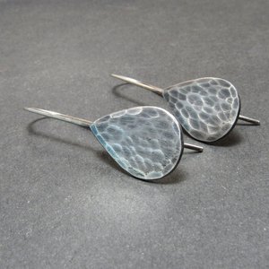 Sideview of hammered sterling silver teardrop earrings, displayed on grey background.
