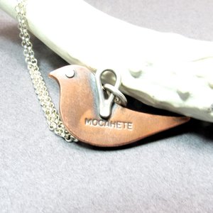Reverse side of mixed metal bird pendant by Mocahete showing makers mark " Mocahete"