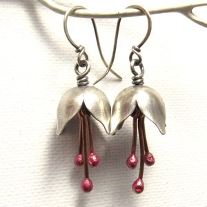 Close up of full length shot of argentium silver and pure reddened copper winter bell flower earrings. Displayed dangling from white branch on white background.