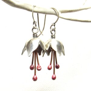 Argentium silver and pure reddened copper winter bell flower earrings. Displayed hanging on white branch on white background.