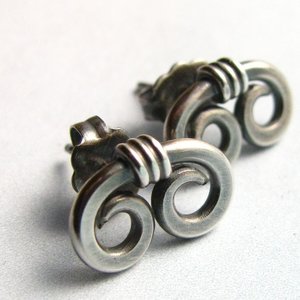 A pair of silver earrings with a unique, twisted design. Each earring features two connected loops, creating a swirling, organic spiral shape.