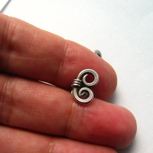 Sterling silver spiral stud earrings photographed in hand.