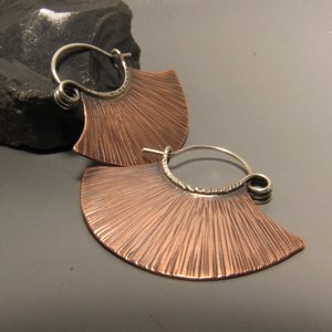 Simple but dynamic copper and silver hoops in a line textured fan shape with a spring style ear wire. !.25 inches tall x 1.25 inches wide. Super lightweight and easy to wear. Copper body, sterling ear wires.