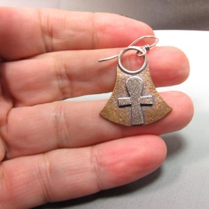 Mixed metal, bronze and silver ankh earrings. Body of earring shaped similar to the egyptian lotus motif with ankh on the front, suspended by silver ring and ear wires. 1.5" tall and 1" wide at widest point.  Displayed in hand.
