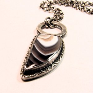 Rugged and handsome Botswana Agate pendant a unisex design perfect for men, women, unisex. Hammered ring as a suspension for the pendant, tooled silver around the stone and sturdy thick 20 inch SS chain with handmade toggle clasp. Pendant - 1.75 inch