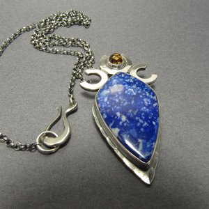 Triple goddess / moon pendant necklace with a faceted citrine and large lapis lazuli cabochon crafted from argentium sterling silver, fine silver. Pendant measures 2 inches from the top and is 7/8 inch across widest part and is suspended on a 18 inch sterling silver chain. Close up of clasp. Displayed on grey background.