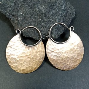 Large hammered bronze hoop earrings with oxidized finish on black background.