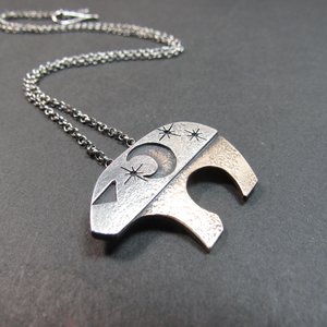 Mixed metal bear pendant necklace by Mocahete on dark background.