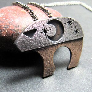 1. Mixed metal bear pendant with moon and stars inspired by Ursa Major photographed against rock.