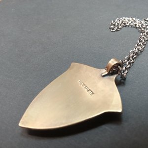 Reverse side of cobra jasper pendant showing the Mocahete makers mark, photo on dark background