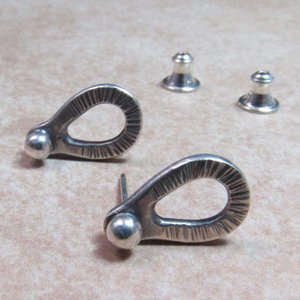 Sterling silver post back or stud earrings shaped like a raindrop and textured. A small orb of silver at the top is the crowning touch. Earrings measure 1/2" long and 1/4" wide. Comes with SS clutch backs.Displayed on light background.