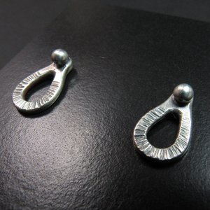 Sterling silver post back or stud earrings shaped like a raindrop and textured. A small orb of silver at the top is the crowning touch. Earrings measure 1/2" long and 1/4" wide. Comes with SS backs not pictured here.Displayed on black background.