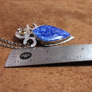Triple goddess / moon pendant necklace with a faceted citrine and large lapis lazuli cabochon crafted from argentium sterling silver, fine silver. Pendant measures 2 inches from the top and is 7/8 inch across widest part and is suspended on a 18 inch sterling silver chain. Displayed against ruler on brown leather.