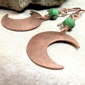 Up close pic of handmade copper crescent moon dangle earrings with faceted green chrysoprase beads. Earrings measure 2 and 1/8" long and the moon is 3/8" wide at widest point.The ear wires are solid, pure copper. Displayed on neutral background with rock.