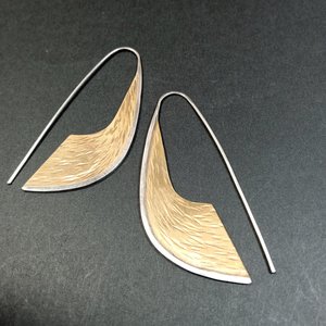 Sword shaped mixed metal earrings in bronze and argentium sterling silver.At 2.25" tall x .75" wide. Displayed on dark background.