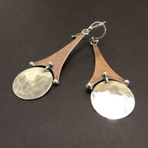 Long copper and silver earrings that resemble the Eiffel tower. 2.5" long, displayed on dark background.