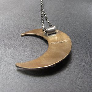 Reverse side of mixed metal crescent moon pendant showing makers mark.
