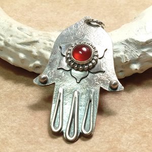 Argentium sterling silver Hamsa pendant necklace with orange red carnelian lotus centerpiece, 18" SS chain. Displayed against antler on neutral background.
