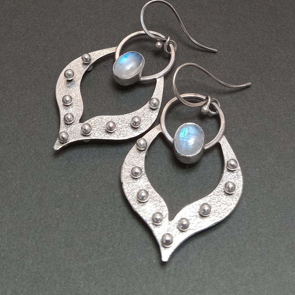 Argentium lotus petal earrings with moonstones. Apx 2" long x 1and 1/8" wide. Displayed on black background.