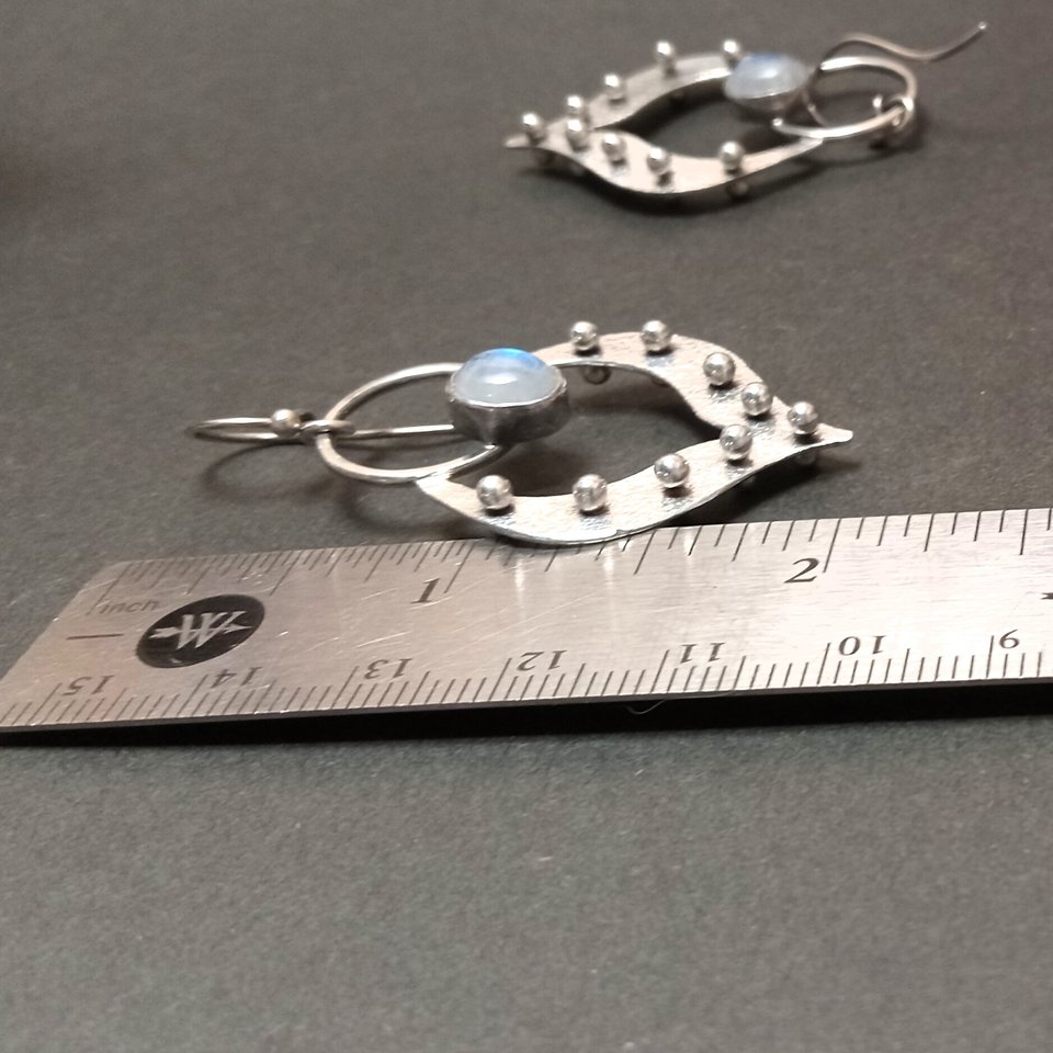 Moonstone earrings in argentium silver displayed against ruler to show length.