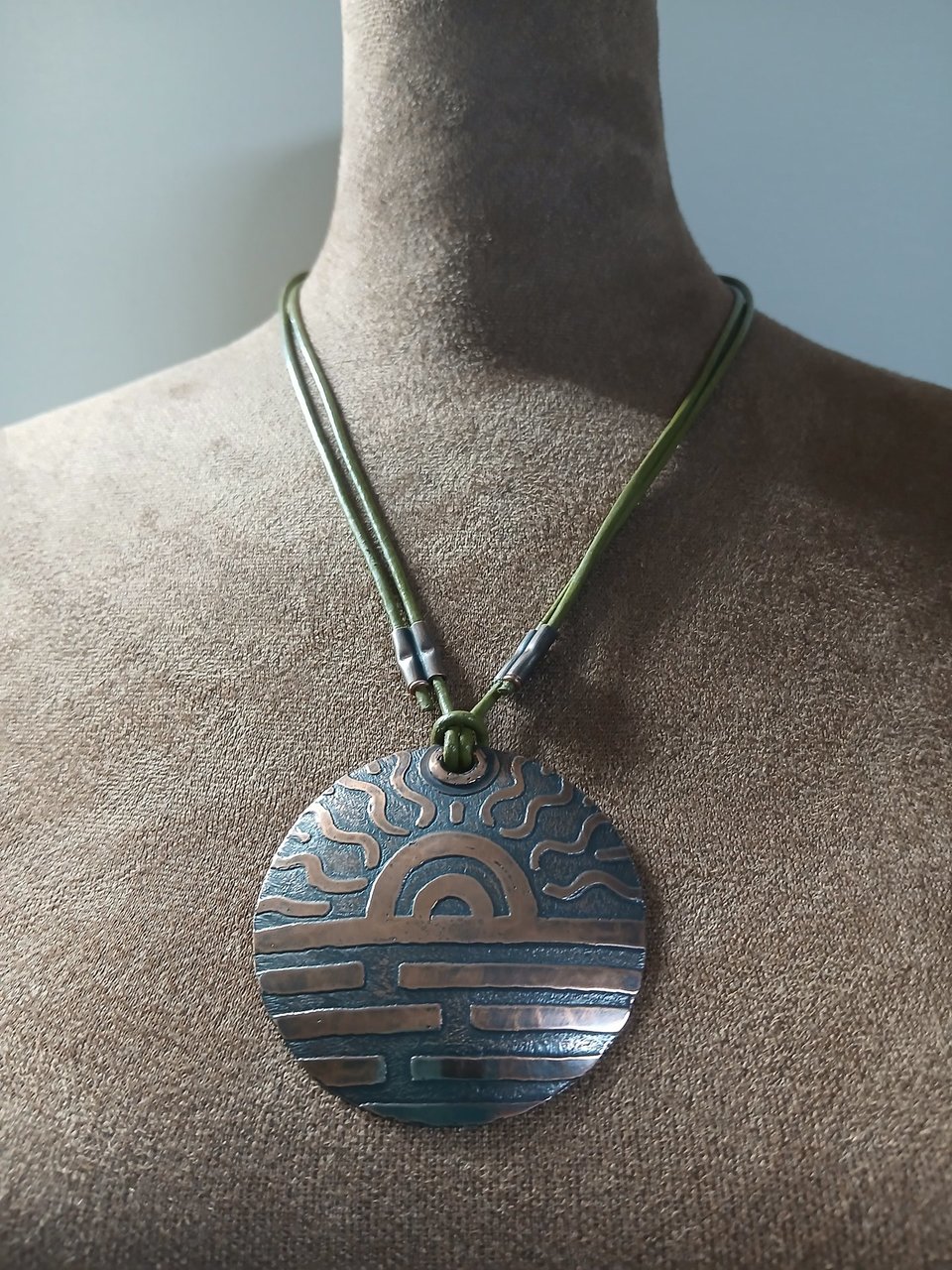 Showing adjusted length of copper pendant hung on leather cord. Displayed on mannequin.