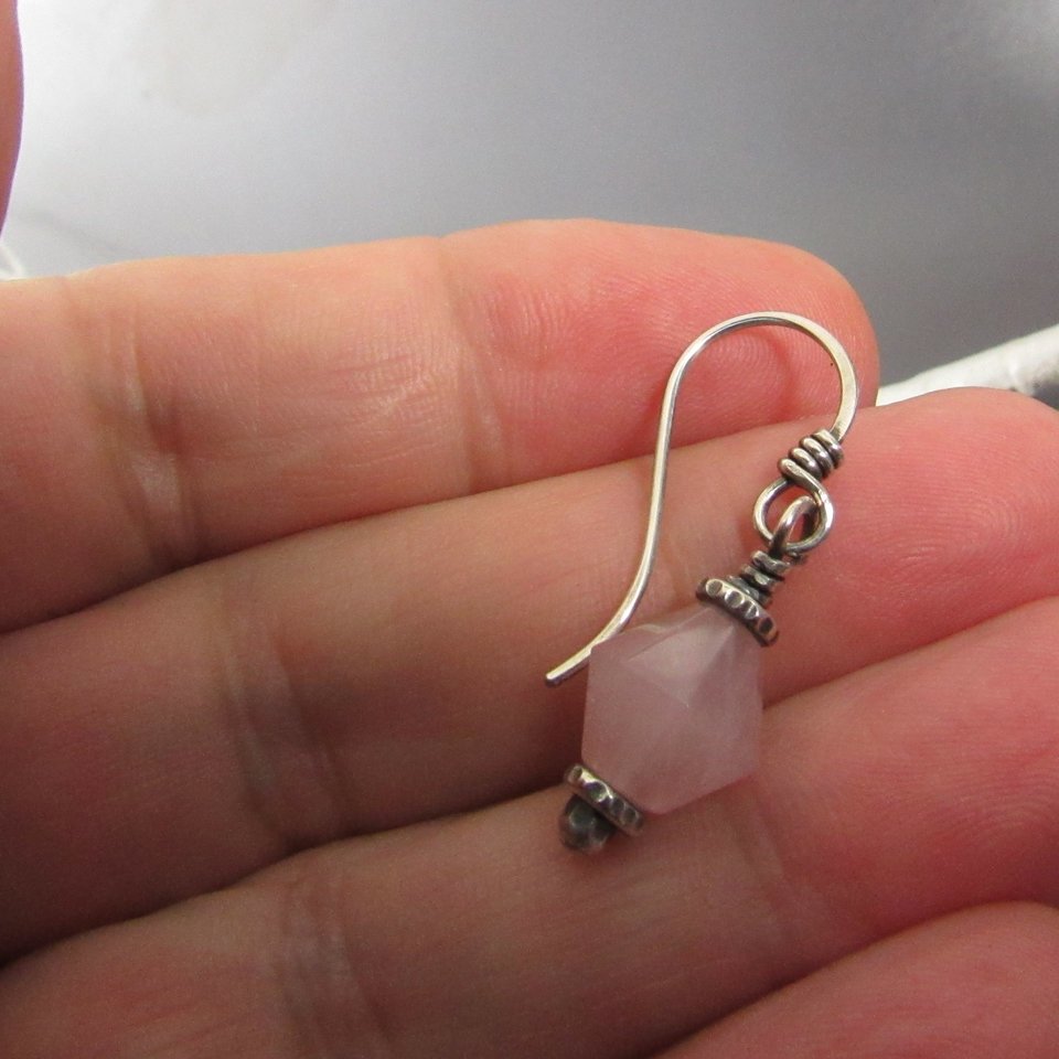 Pink quarts earring displayed in hand.