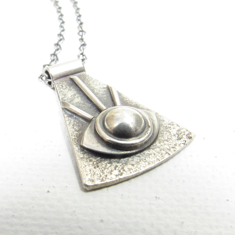 Up close view of eye of providence pendant necklace in argentium silver. White background.