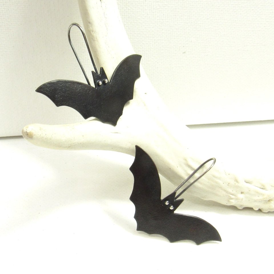  Bat earrings in mixed metal. Displayed on white antler and background.