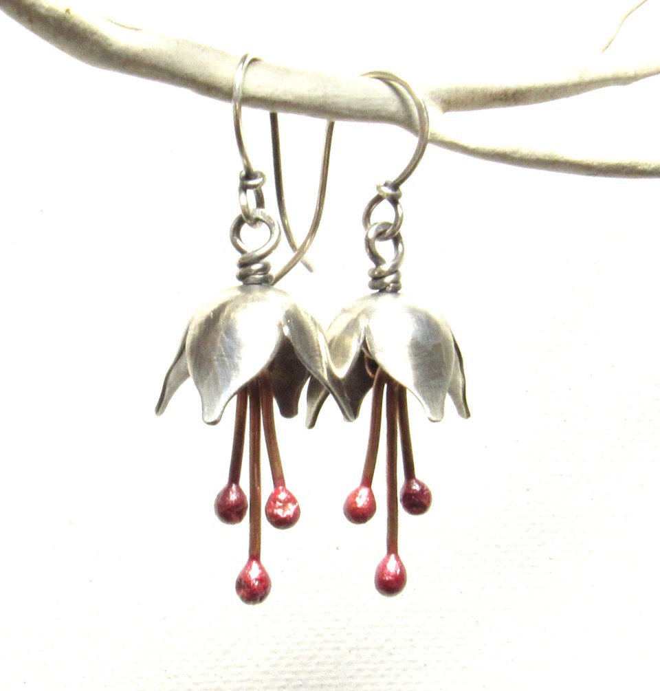 Argentium silver and pure reddened copper winter bell flower earrings. Displayed hanging on white branch on white background.