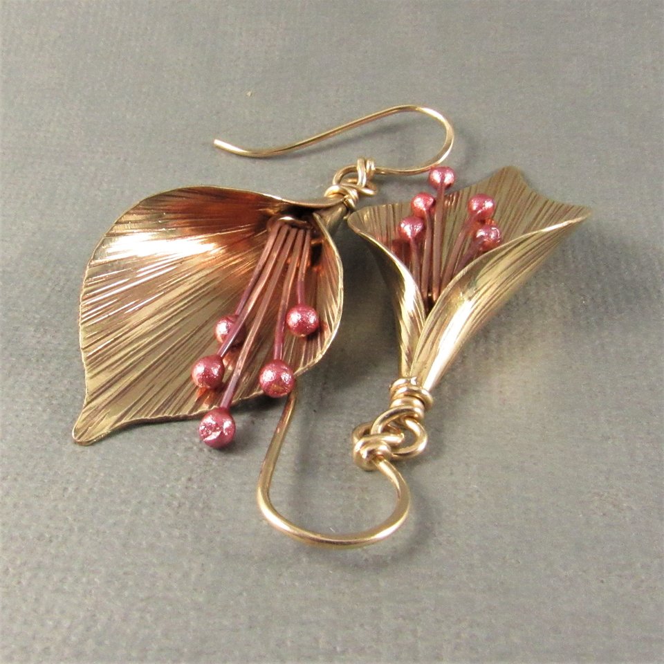 Handcrafted, unique mixed metal lily flower earrings are lovely with the warm metals of gold, bronze and copper. Reddened copper stamens tinkle gently.2 and 1/8" or 6cm long and .75"  or 1.9cm wide at widest point.