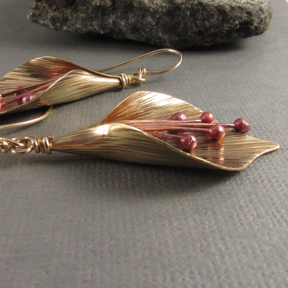 Handcrafted, unique mixed metal lily flower earrings are lovely with the warm metals of gold, bronze and copper. Reddened copper stamens tinkle gently.2 and 1/8" or 6cm long and .75"  or 1.9cm wide at widest point.