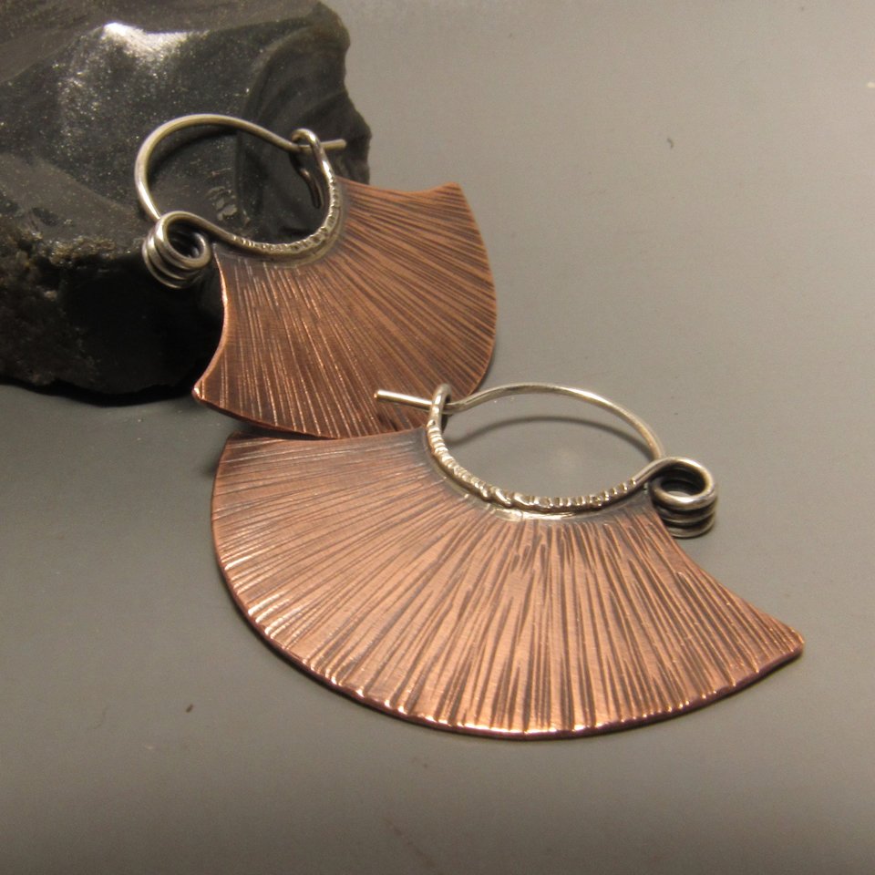 Simple but dynamic copper and silver hoops in a line textured fan shape with a spring style ear wire. !.25 inches tall x 1.25 inches wide. Super lightweight and easy to wear. Copper body, sterling ear wires.