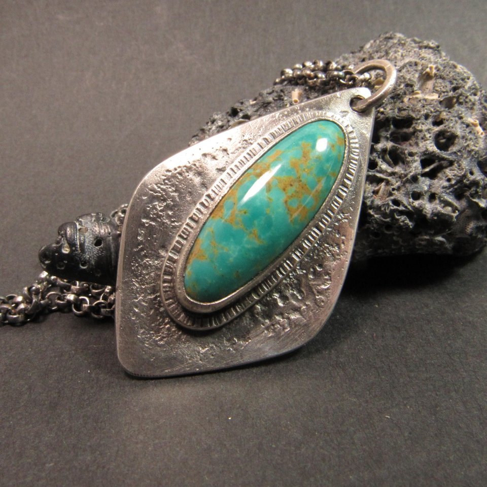 Stunning Number 8 mine turquoise is at the heart of this argentium sterling silver Organic shaped geometric pendant design. Blue green in color with brown matrix, textured silver background.