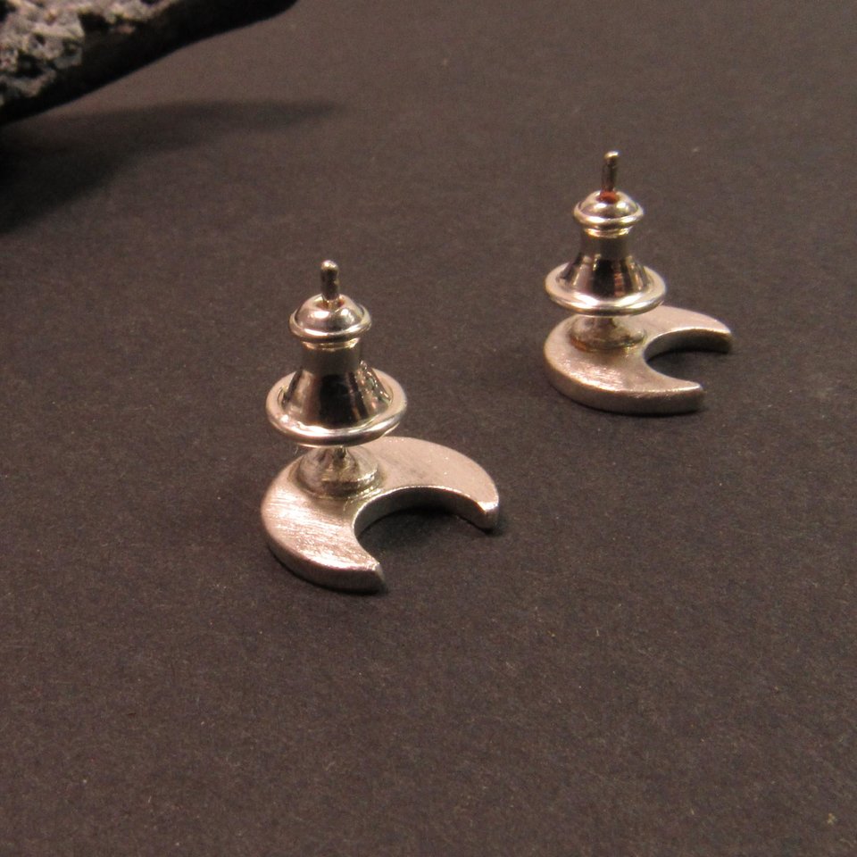 A pair of silver crescent moon stud earrings with bullet clutch backs. The earrings have a simple, modern design and are perfect for everyday wear.