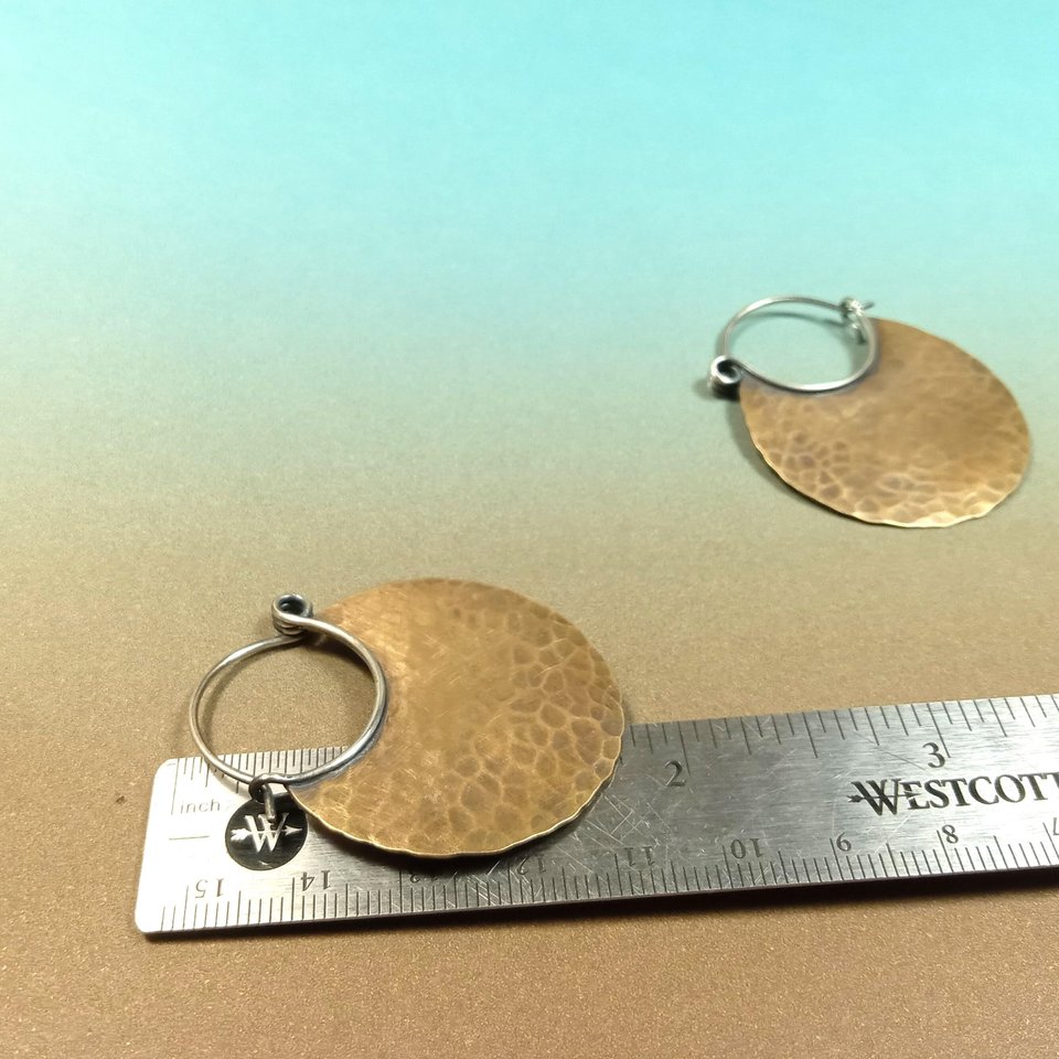 Mixed metal hammered hoops against ruler to show height, blue and brown background.