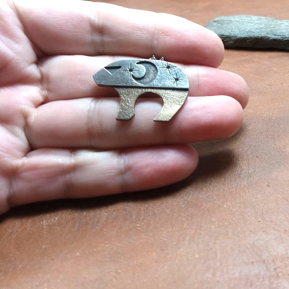 Mixed metal bear pendant by Mocahete photographed in hand.