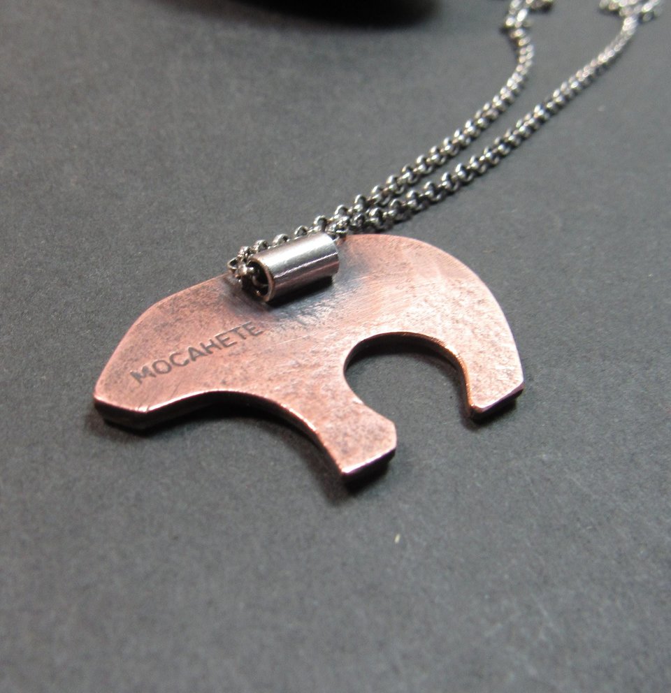 Reverse side of mixed metal bear pendant showing bail and makers mark "Mocahete" The necklace is displayed against a dark background.
