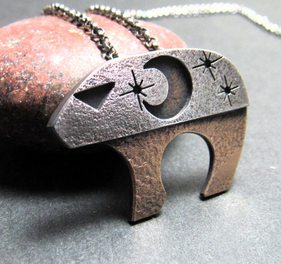 1. Mixed metal bear pendant with moon and stars inspired by Ursa Major photographed against rock.