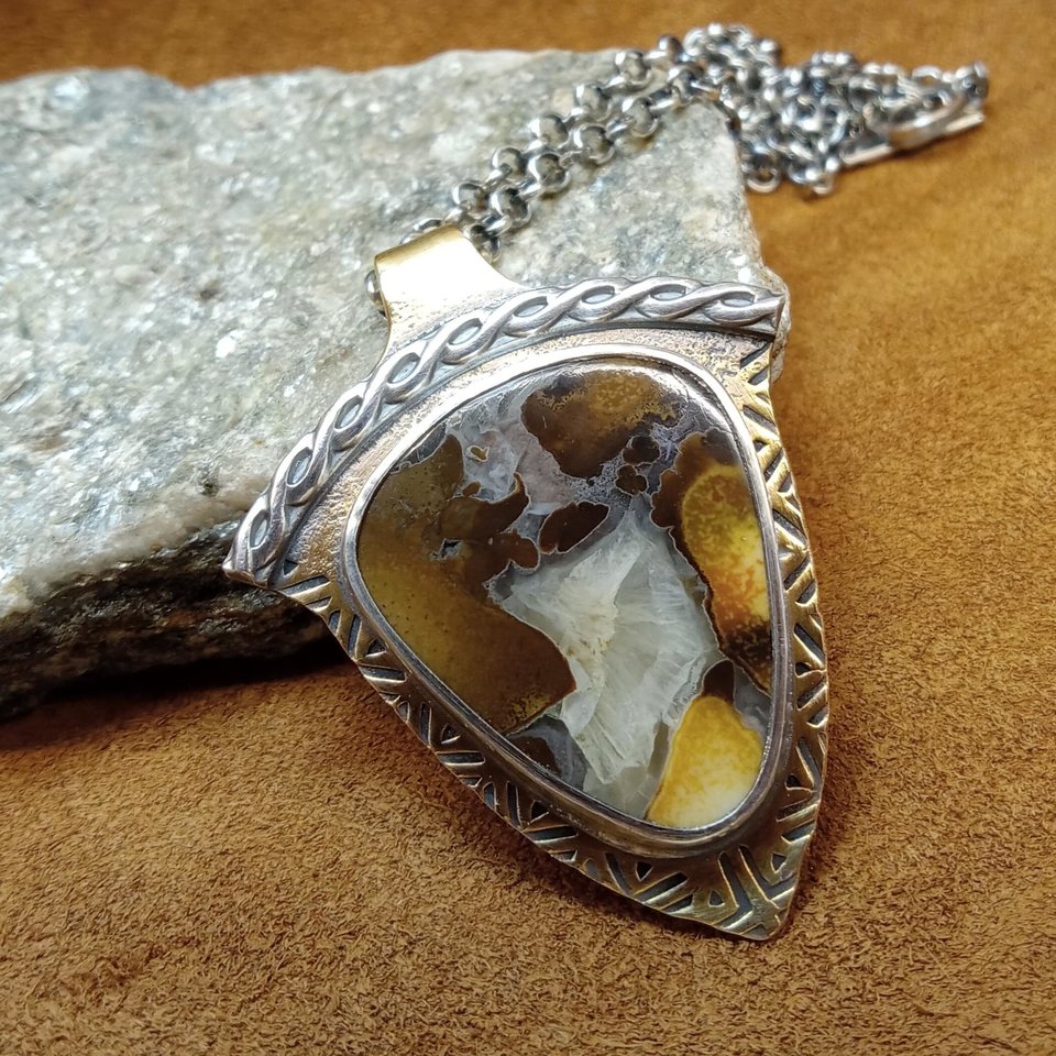Cobra jasper pendant showing swirls of earthy colors in its matrix. SS chain and handmade findings. Photo against rock on leather.