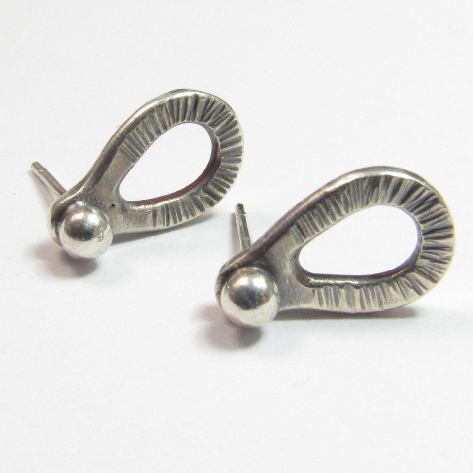 Sterling silver post back or stud earrings shaped like a raindrop and textured. A small orb of silver at the top is the crowning touch. Earrings measure 1/2" long and 1/4" wide. Comes with SS backs not pictured here.Displayed on light background.