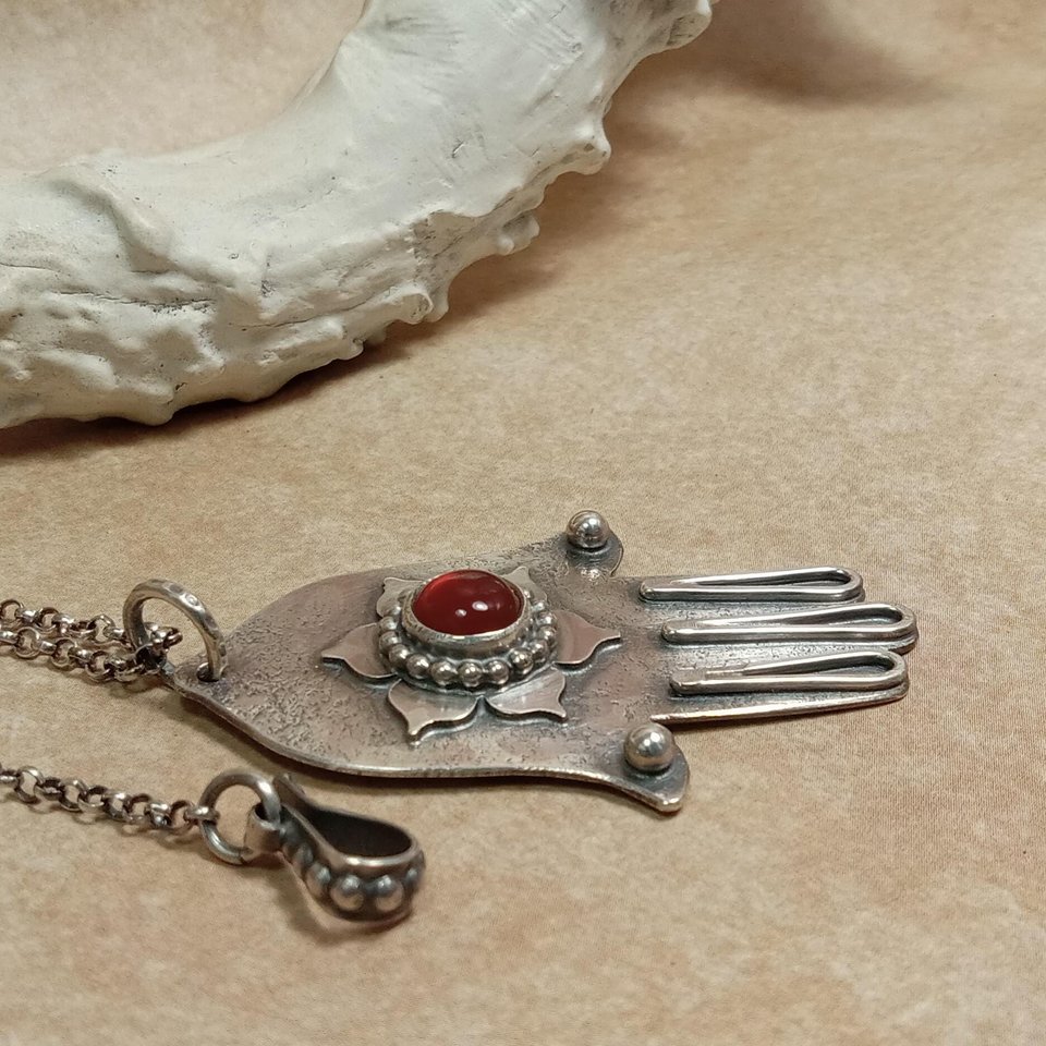 Side view of carnelian and SS Hamsa necklace showing hook closure. Displayed on neutral background with antler.