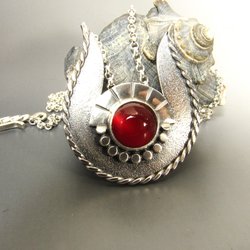 This handcrafted Egyptian inspired Hathor necklace was rendered from argentium sterling silver and a luminous 10mm carnelian cabochon set in fine silver which represents the sun. The pendant measures a bit over 1.5 inch T x 1.25 WChoose chain length