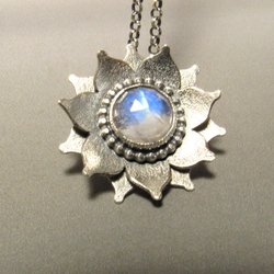 argentium sterling silver moonstone lotus pendant with two layers of petals and nestled in the center is a large faceted blue flash moonstone cabochon. Silver is oxidized and pendant is suspended from an 18" sterling silver chain.
