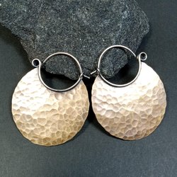 Large hammered bronze hoop earrings with oxidized finish on black background.