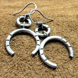 Bold and simple contemporary sterling silver earrings crafted from Argentium have lovely swingy movement. The double open hoop design allows for them to articulate. Lightweight and comfortable  at only 5 grams per earring. 1.75” long and 7/8” at widest point. Displayed on brown leather.