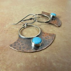 May include: A pair of handmade earrings with a hammered copper fan shape and a turquoise stone set in silver. The earrings have a silver hoop and a silver hook.