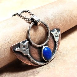 Side view of handcrafted mixed metal lotus pendant in argentium silver and copper with lapis lazuli cabochon. Displayed on neutral background.